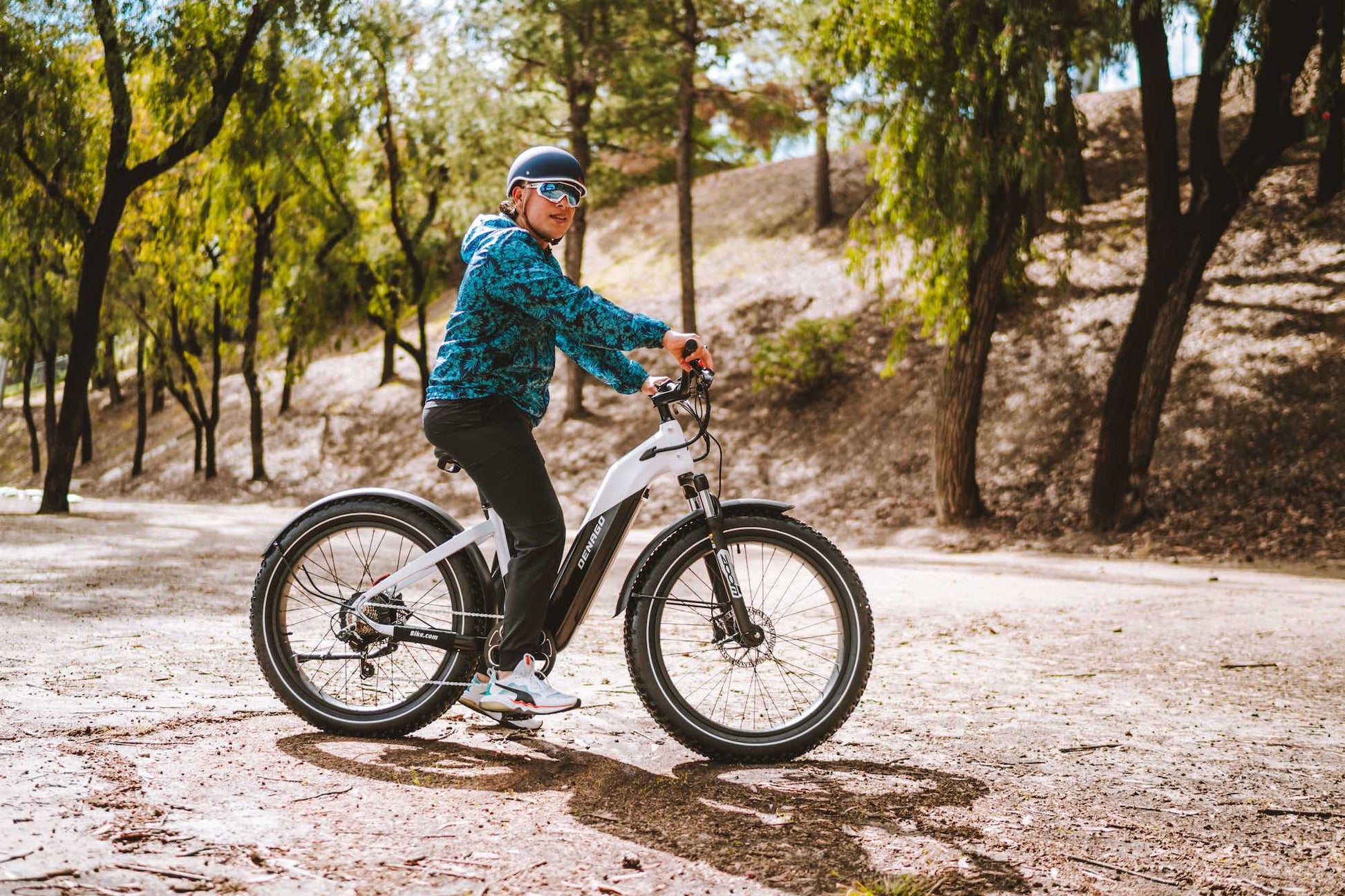 A man with a teal jacket standing with an electric mountain bike